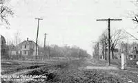 nearly empty dirt road with a few buildings and telephone poles