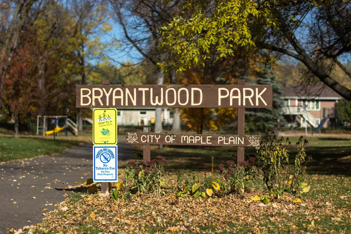 wood sign reading Bryantwood Park with fallen leaves on the ground