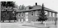 two story elementary school building surrounded by pine trees