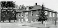 two story elementary school building surrounded by pine trees