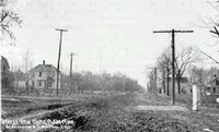 nearly empty dirt road with a few buildings and telephone poles