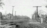 nearly empty dirt road with a few buildings and telephone poles